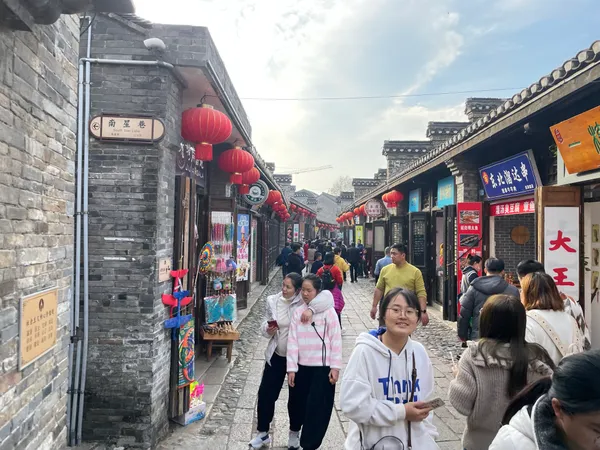 People walking along a historic shopping street lined with gray-brick buildings