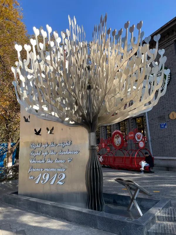 A branching metal tree sculpture at Nanjing's 1912 district, inscribed “Light up the night”